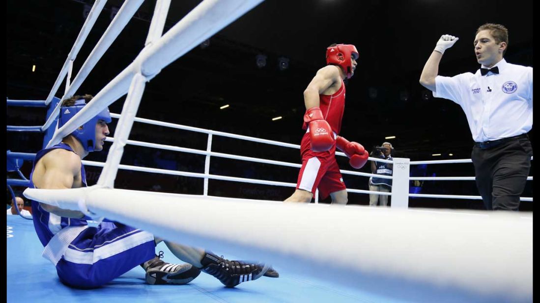 Yakup Sener, left, of Turkey is counted after being knocked down by Uktamjon Rahmonov, center, of Uzbekistan during the round of 16 light-welterweight (64 kilogram) match. Rahmonov was awarded a 16-8 points decision.