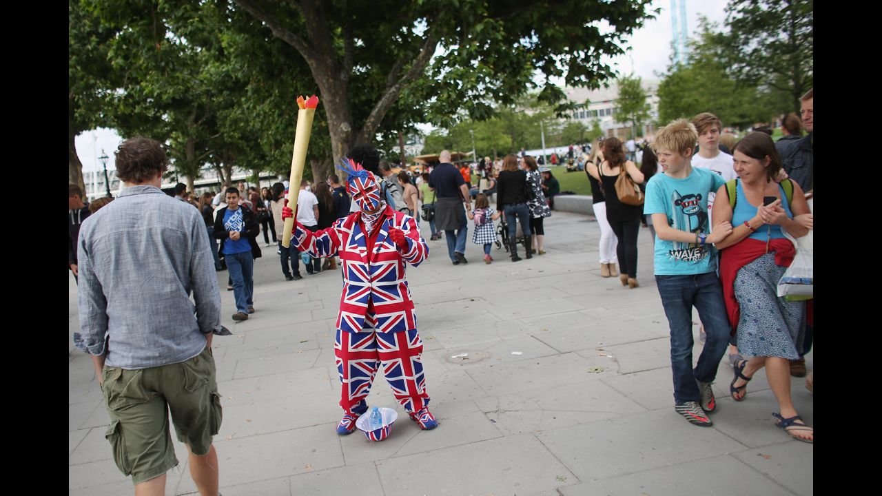 A performer dressed in a Union Flag suit and holding a mock Olympic flame entertains crowds on the South Bank in London.