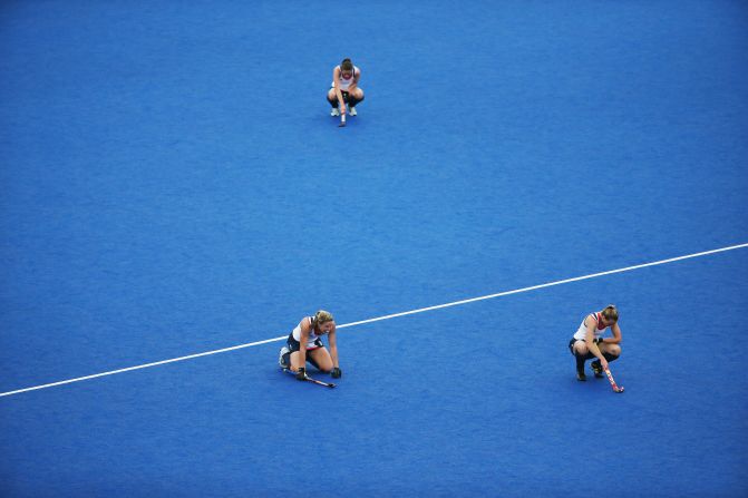 Members of Great Britain's women's hockey team slump to the ground after losing to China during a preliminary match.