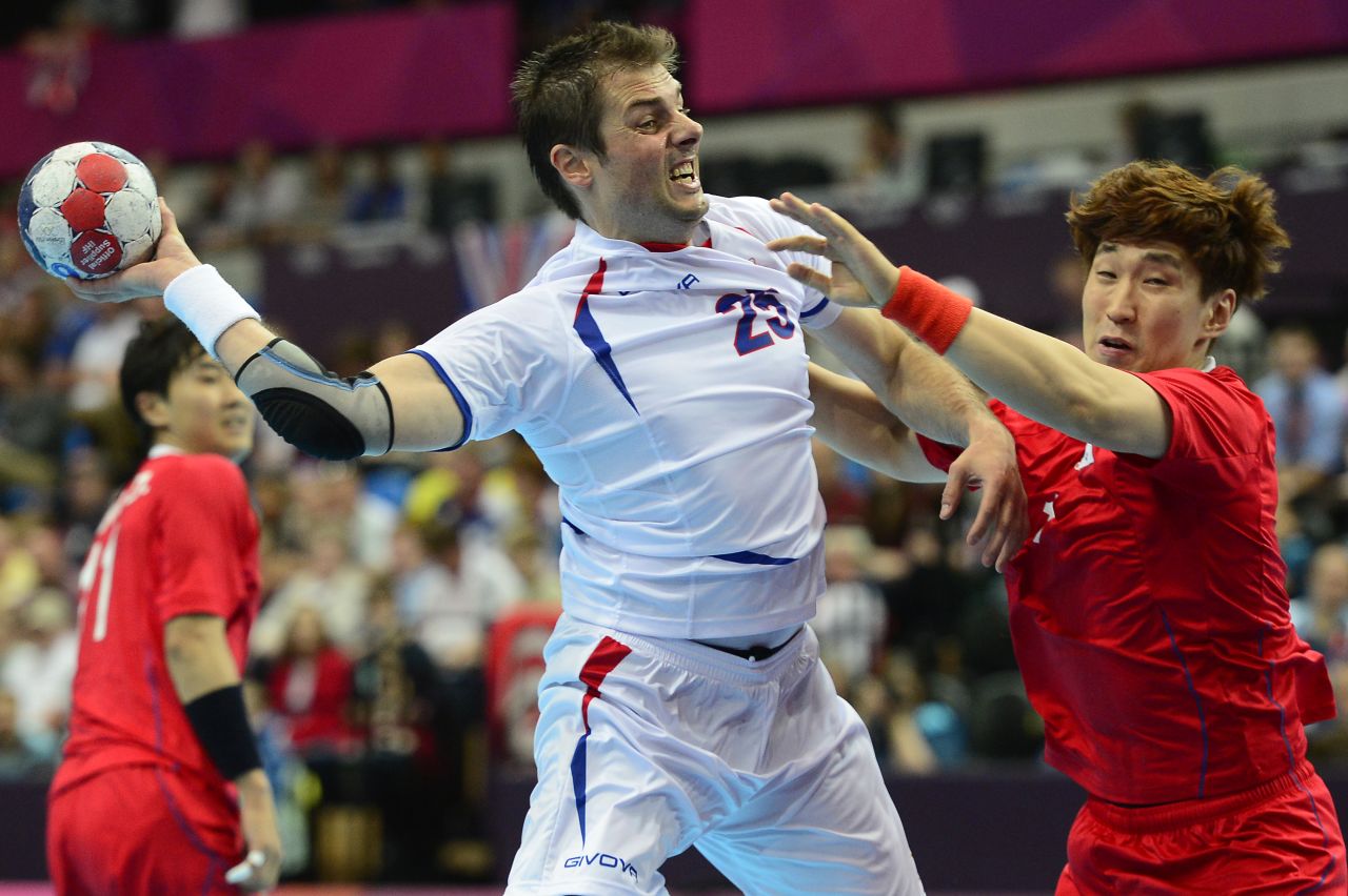 Serbia's left back Momir Rnic, left, jumps to shoot during a men's preliminary handball match against South Korea.