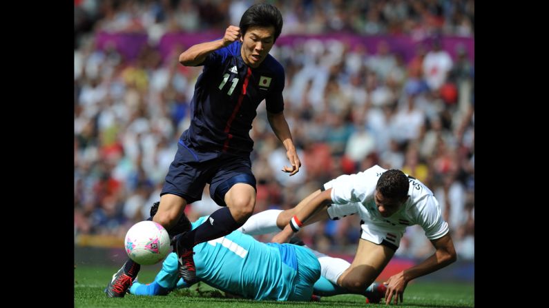 Japan's Kensuke Nagai, left, scores past Egypt's goalkeeper Ahmed Al-Shenawi, center, and Egypt's defender Saadeddine Saad, right, during the quarter final football match Saturday.