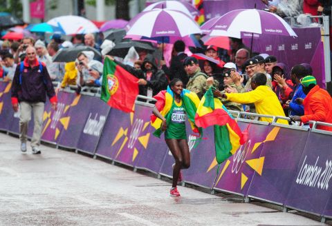 Wrapped in her nation's flag, Tiki Gelana of Ethiopia celebrates winning the women's marathon.