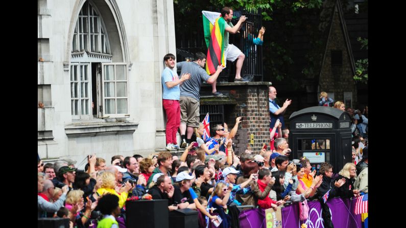 Spectators take photographs and shout encouragement to the runners in the women's marathon.