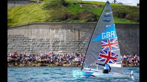 Ben Ainslie of Great Britain hoists the Union Jack and acknowledges the cheers from fans after winning the gold medal in the finn class medal race in Weymouth, England.