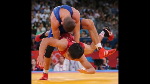 Peter Modos of Hungary, top, wrestles with Arsen Eraliev of Kyrgyzstan, bottom, during the men's Greco-Roman 55-kilogram wrestling qualification.