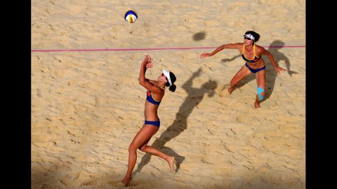 Xi Zhang of China, left, sets the ball for teammate Chen Xue during the women's beach volleyball quarterfinal match against Austria.