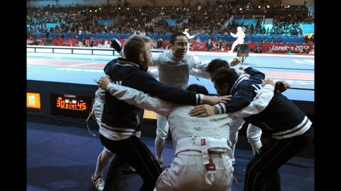 Team Japan celebrates defeating China during the men's foil team quarterfinals fencing event at the ExCeL center Sunday.