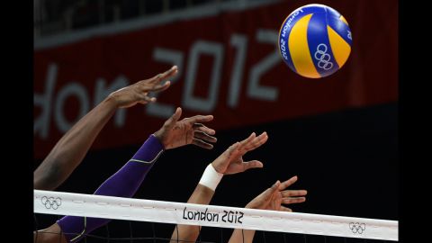 Members of the Dominican Republic women's volleyball team attempt to block a shot during a preliminary match against Algeria.