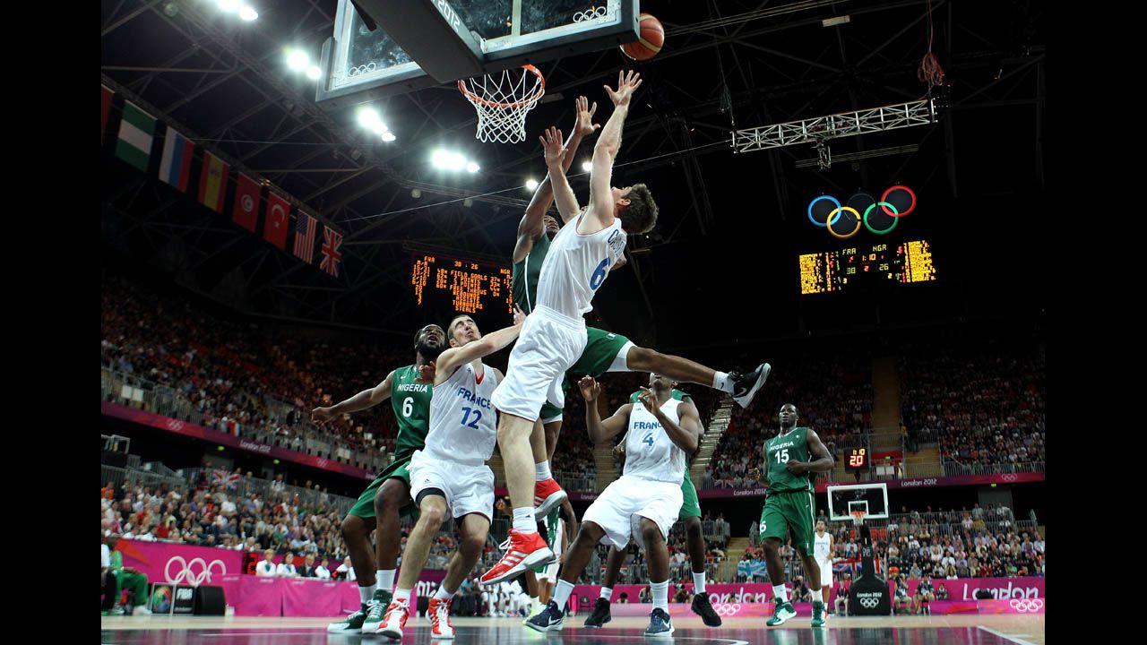 Fabien Causeur of France, center, drives for a shot attempt against Nigeria during the men's basketball preliminary round match.