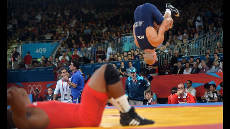 Damian Janikowski of Poland flips out as Pablo Enrique Shorey Hernandez of Cuba lies on the mat during the quarterfinal of the men's Greco-Roman 84-kilogram event.