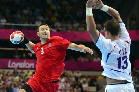 Hungarian back Ferenc Ilyes, left, takes a shot in front of Serbia's Momir Ilic during the men's preliminary Group B handball match.