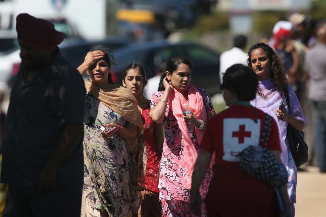 People wait for information in front of the temple as law enforcement officers secure the area.