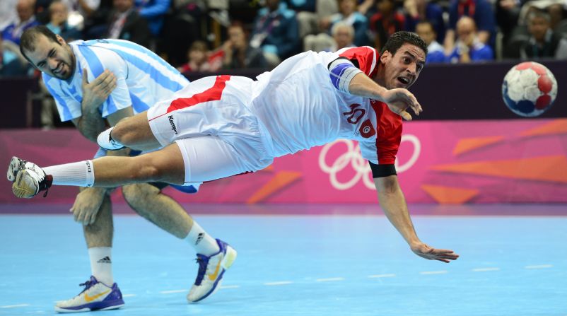 Tunisian centerback Kamel Alouini, right, jumps and shoots past Argentina's Leonardo Facundo Querin during the men's preliminary Group A handball match.