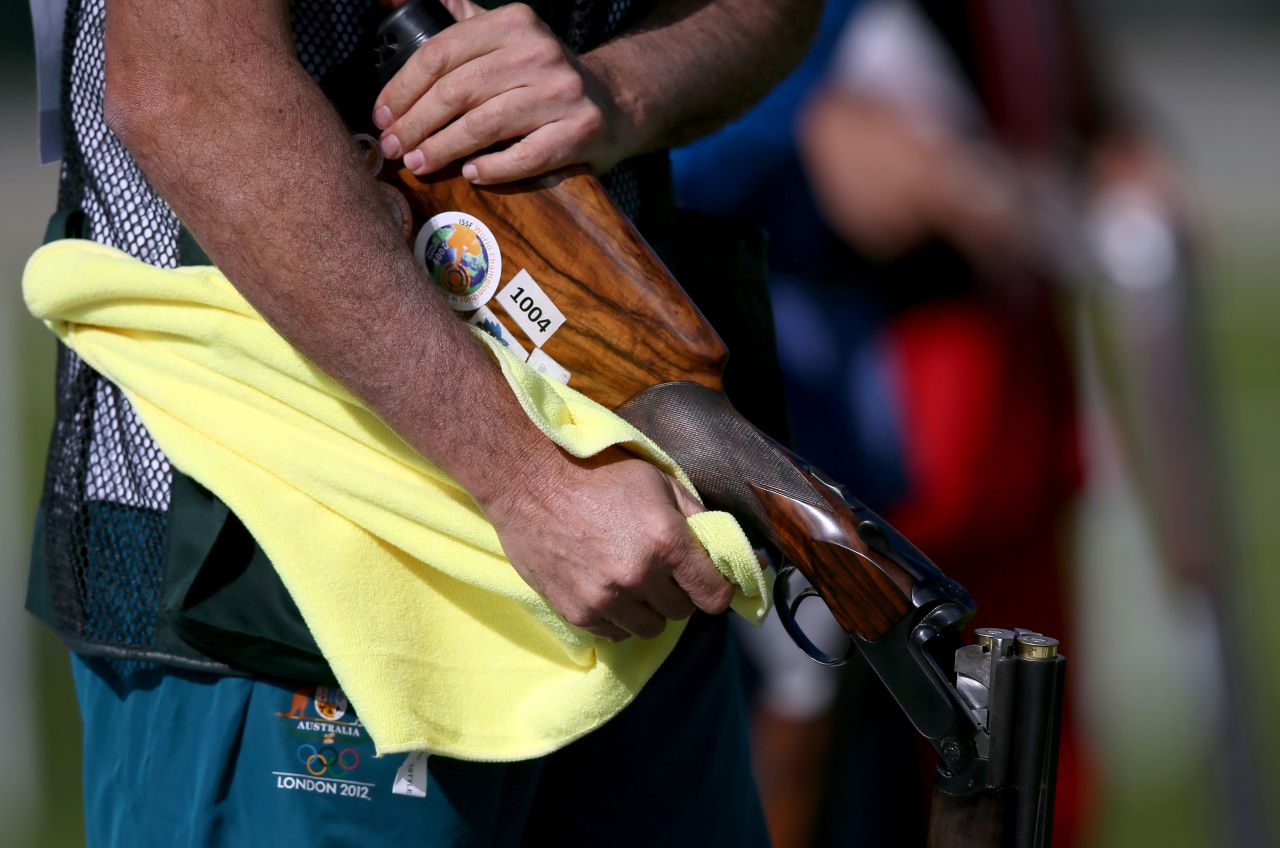 Michael Diamond of Australia wipes down his gun as he competes in the men's trap shooting qualification at the Royal Artillery Barracks Excel Centre.