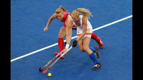 Nicola White, in red,  of Great Britain and Margot van Geffen of the Netherlands contest for the ball during  women's hockey play.