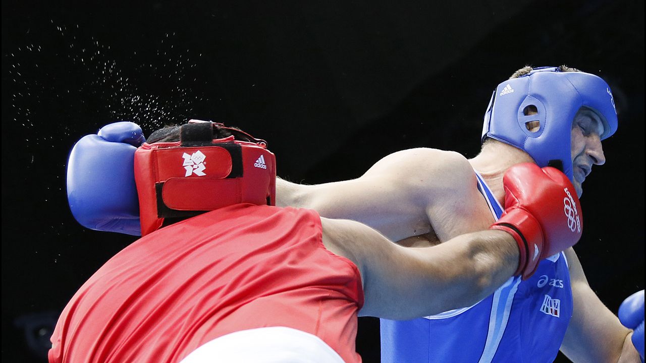 Mohammed Arjaoui of Morocco, in red, and Roberto Cammarelle of Italy, in blue, trade punches during their super heavyweight boxing quarterfinal.