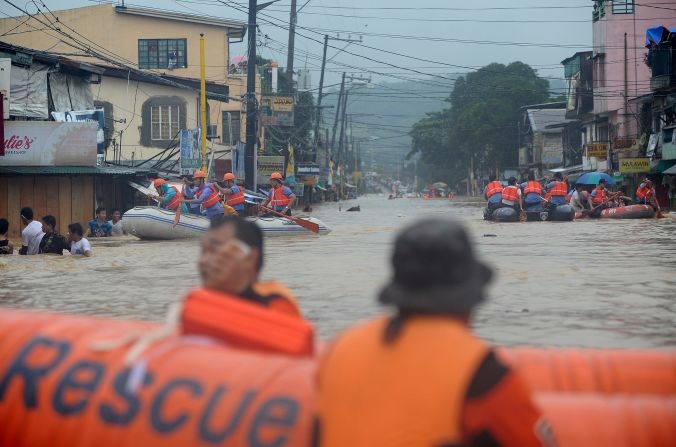 Rescuers maneuver down a flooded street as they evacuate residents in the village of Tumana in suburban Manila on Tuesday, August 7, after torrential rains inundated most of the capital.
