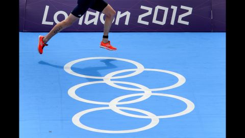 Britain's Alistair Brownlee runs over Olympic rings on his way to a win in the men's triathlon.
