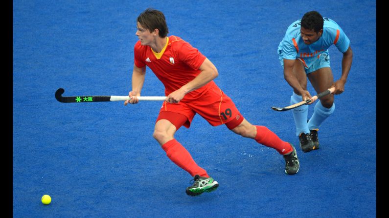 Felix Denayer, left, of Belgium dribbles past Birendra Lakra of India during the field hockey preliminary round match between India and Belgium.