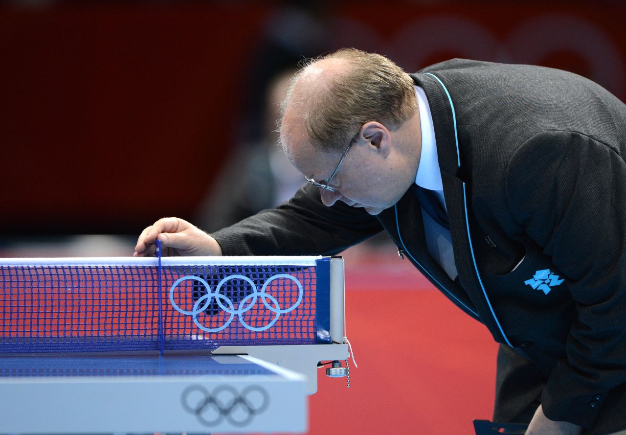 An Olympic official comforts the table-tennis table after it absorbs another butt-kicking.
