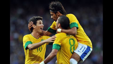 Brazil midfielder Oscar, left, and Brazil forward Neymar, right, congratulate goal scorer Brazil defender Romulo, second right, during the London 2012 Olympic men's football semifinal match between Brazil and South Korea.