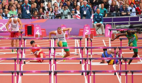 Balazs Baji, center, of Hungary leads the pack as Xiang Liu of China falls over a hurdle in the men's 110-meter hurdles round 1 heats.