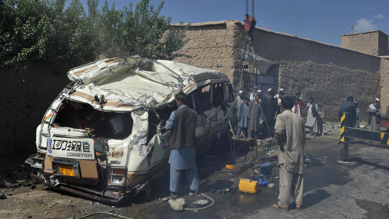 Afghan policemen and villagers at the scene where a civilian minibus was hit by a remote-controlled bomb in Paghman district of Kabul on August 7, 2012. 