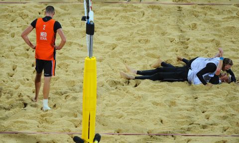 Rich Schuil of Netherlands looks dejected as Julius Brink and Jonas Reckermann of Germany celebrate match point during the men's beach volleyball semifinal match between Germany and the Netherlands.