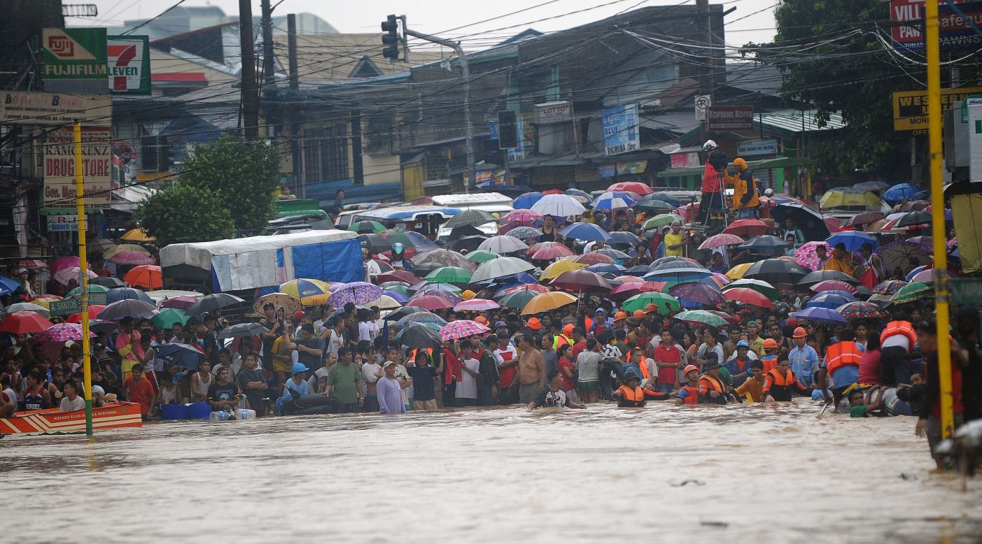 Residents wait for family members to be rescued at the end of a flooded street in the village of Tumana, a suburb of Manila on Tuesday, August 7.