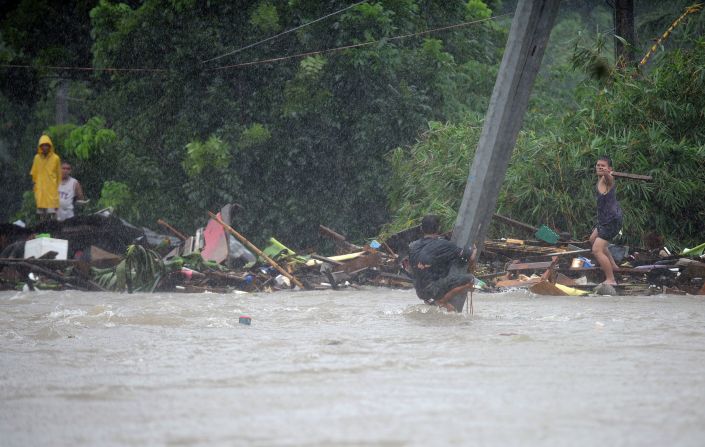 A man clutches a pole in floodwaters after a river overflowed following torrential rain in Manila.