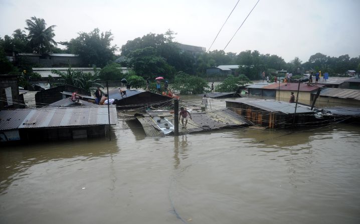 Residents seek shelter on the roofs of their homes as floodwaters continue to rise in Manila.