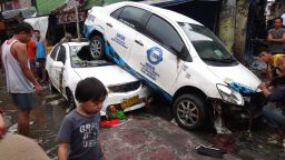 Residents look at vehicles washed up by floodwaters in Manila on August 8, 2012.