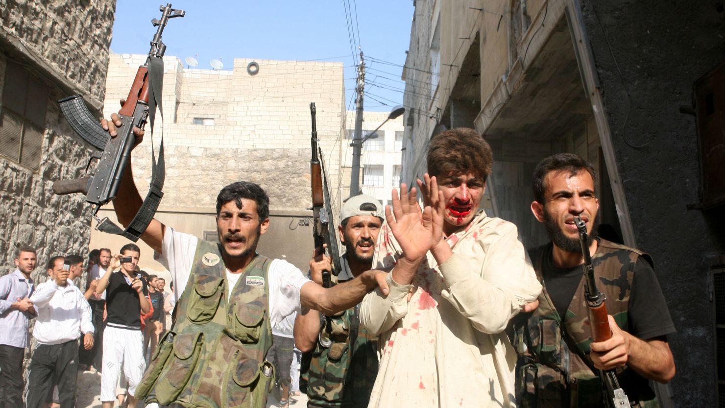Rebel Free Syrian Army fighters march a captured policeman who they believe is a pro-regime militiaman on July 31, 2012. 
