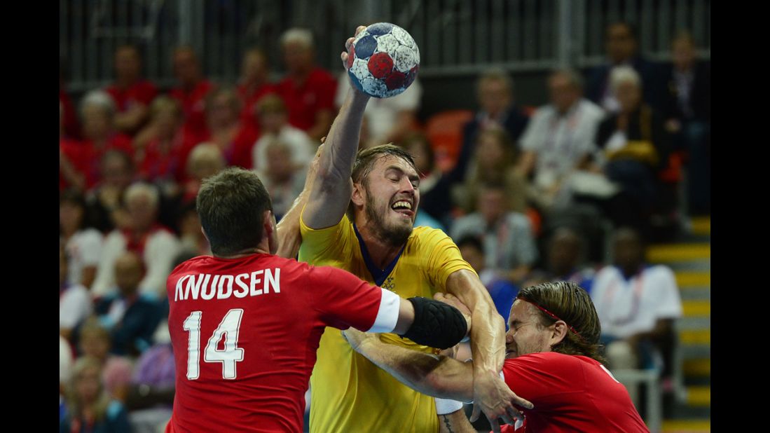 Sweden's right back Kim Andersson, center, vies with Denmark's pivot Michael Knudsen during the men's quarterfinal handball match.