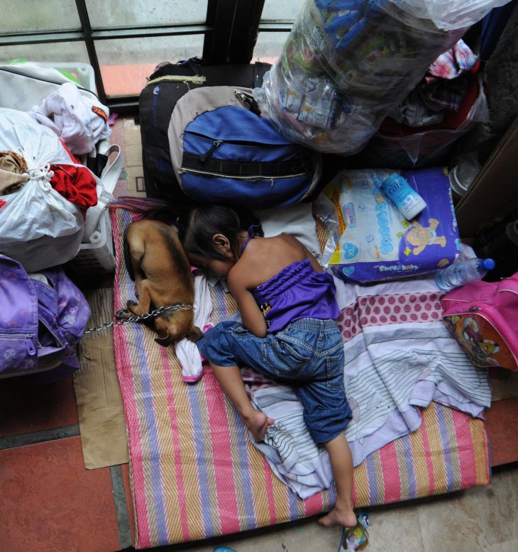A child, one of the thousands of residents affected by the severe floodings, sleeps next to the family's dog at a temporary evacuation center.