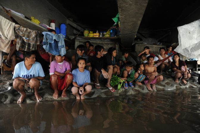 A group of Filipino farm workers huddles beneath a bridge north of Manila on Wednesday. Flooding caused by 10 days of torrential rains, worsened by the overflowing of three dams, has paralyzed 80% of the city. More than 70 people have died and 263,000 residents have been displaced. 