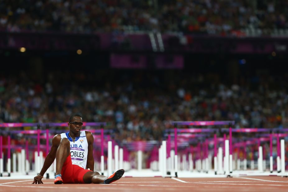 Dayron Robles of Cuba waits on the track after pulling up injured in the men's 110-meter hurdles final.
