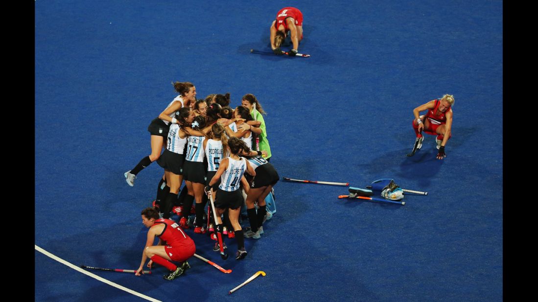 Anne Panter, Alex Danson and Crista Cullen of Great Britain slump to the ground as the Argentinian team celebrate their victory during the women's hockey semifinal match.