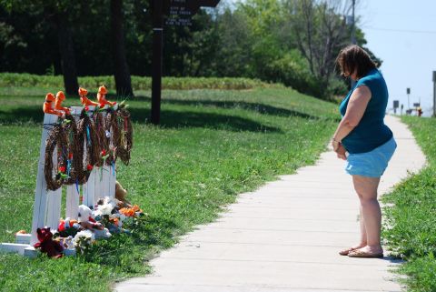 Peggy Renner-Howell bows her head after laying flowers Tuesday at a makeshift memorial near the Sikh Temple of Wisconsin in Oak Creek.