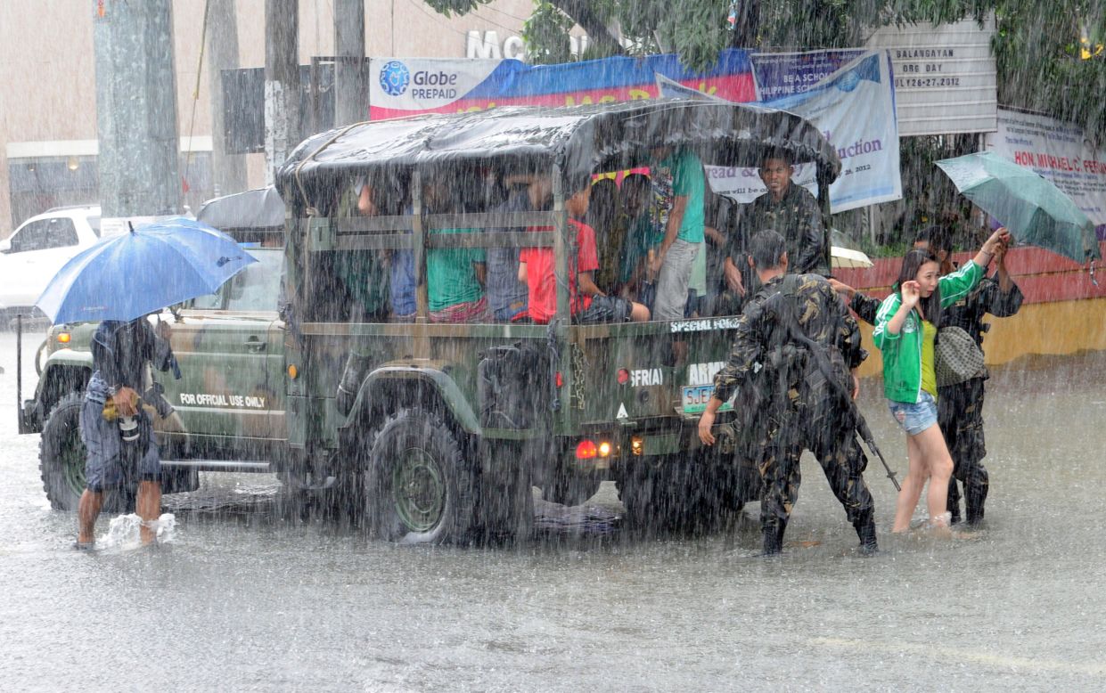 Philippines army soldiers assist people during heavy rains north of Manila on Wednesday, August 8.