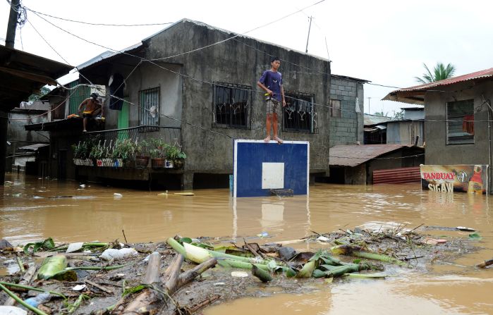 A boy stands on a basketball backboard among flooded homes in San Mateo, Rizal.