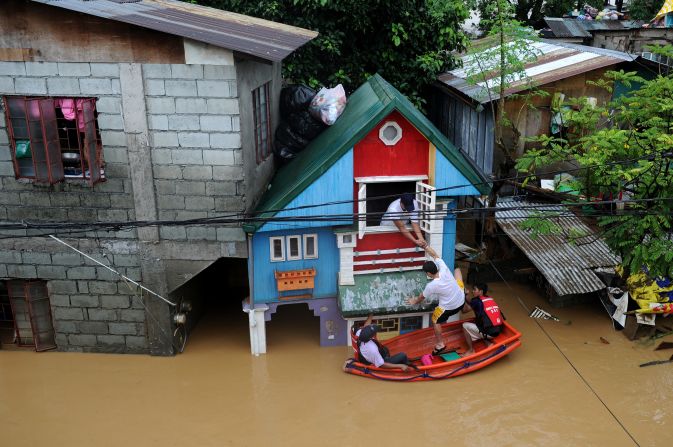 Rescue workers help people return to their home near a river that overflowed in the Manila suburb of San Mateo, Rizal.