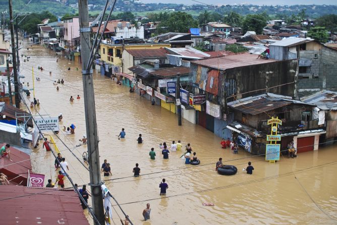 Residents cross floodwaters Wednesday during heavy flooding in Manila.