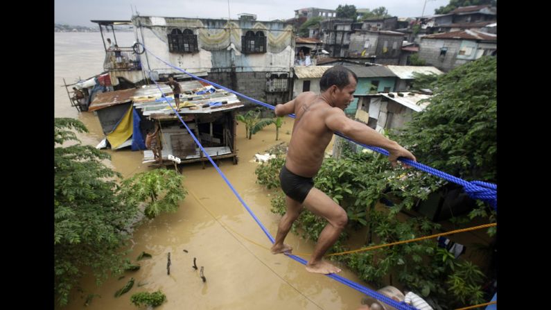 A man crosses the floodwaters on a rope in Pasig City, east of Manila, on Thursday, August 9.