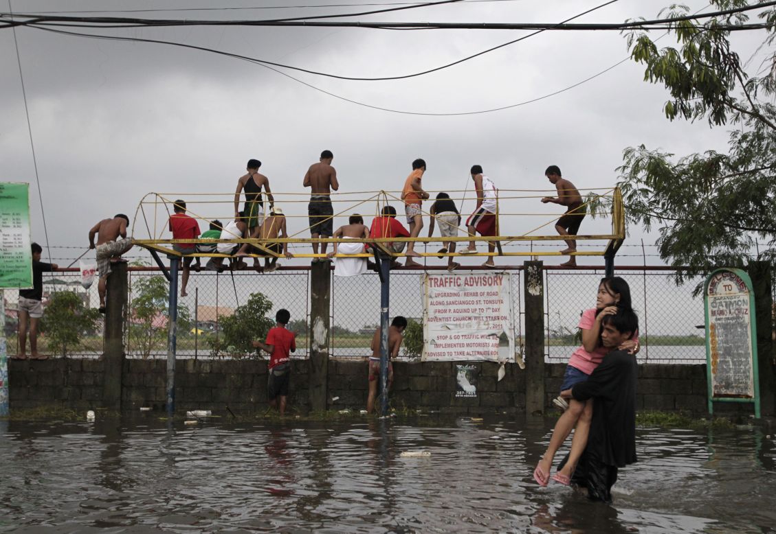 Residents wade through floodwaters caused by monsoon rains in Catmon, Malabon, north of metro Manila.