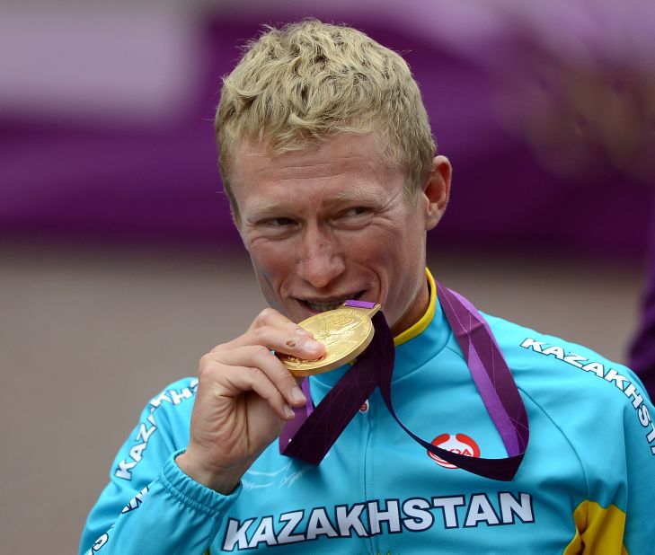 Alexander Vinokourov of Kazakhstan bites his gold medal after winning the men's road race cycling event.