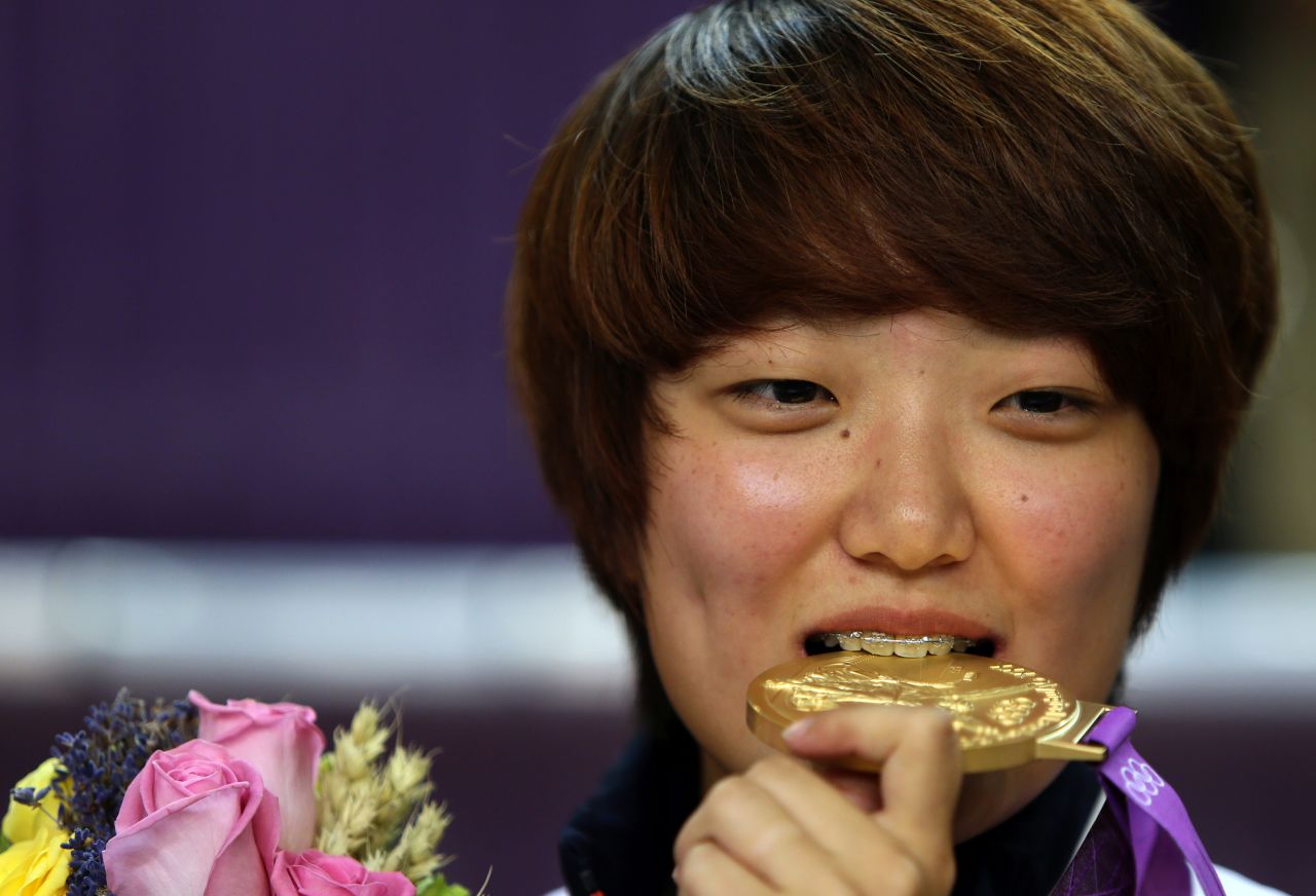 South Korea's Kim Jang-mi bites her gold medal on the podium after victory in the women's 25-meter pistol final.