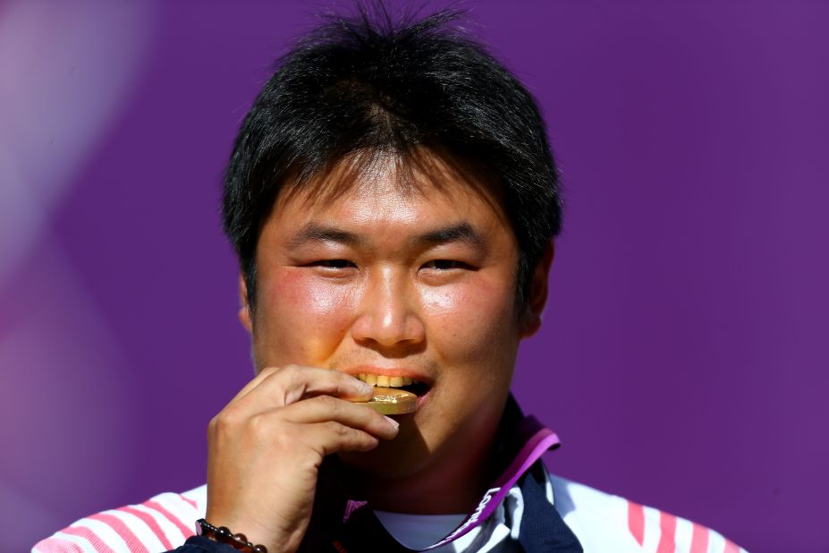Oh Jin-hyek of South Korea bites his gold medal after winning an archery competition. 