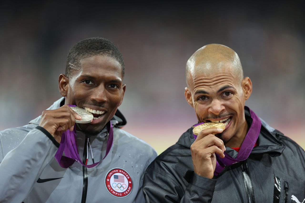 Silver medalist Michael Tinsley of the United States and gold medalist Felix Sanchez of Dominican Republic bite their medals after the men's 400-meter hurdles final.