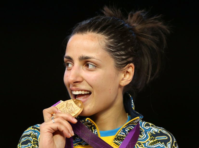 Yana Shemyakina of Ukraine bites her gold medal after defeating Britta Heidemann of Germany in the women's epee individual fencing finals.
